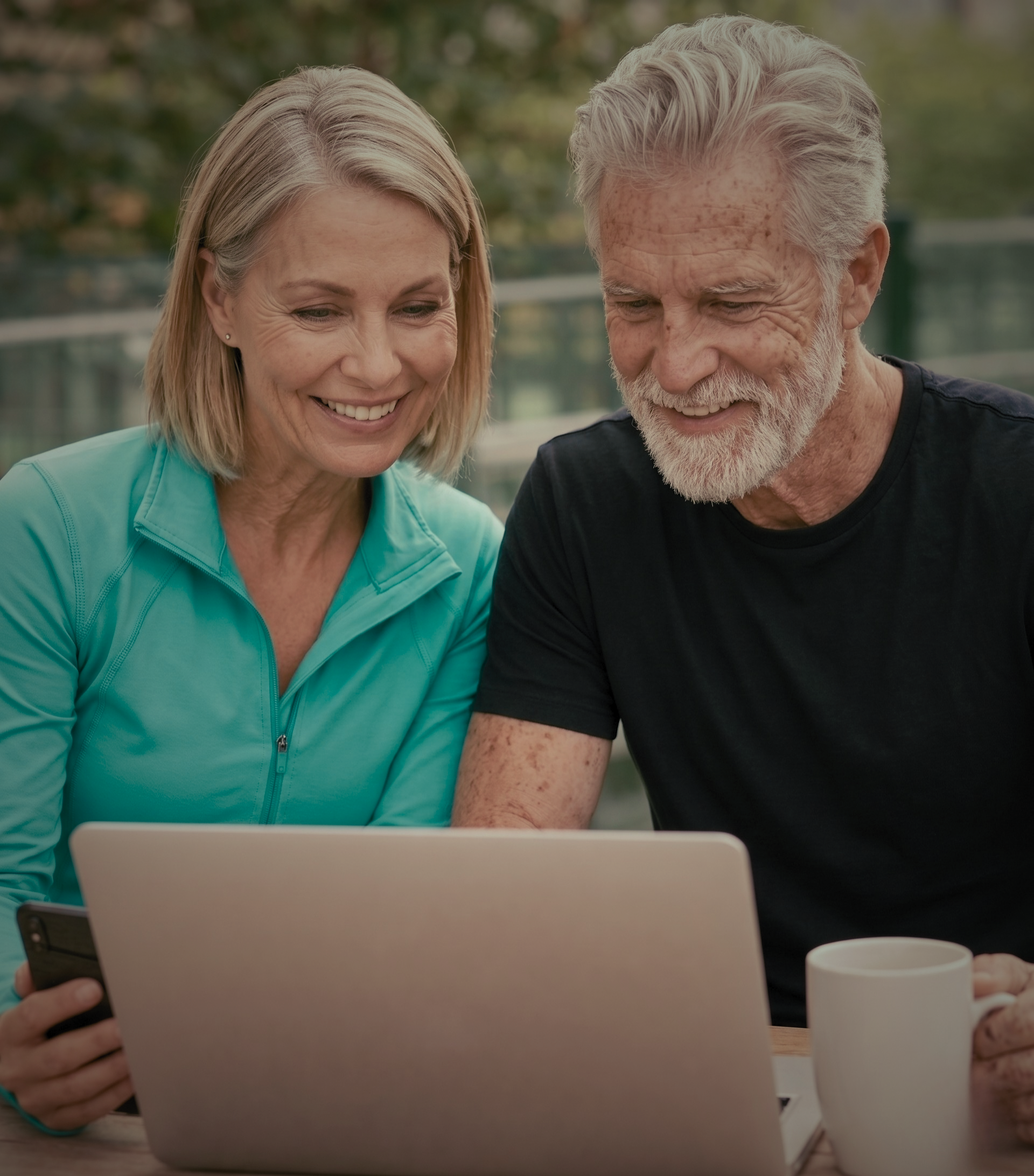Two adults looking at a laptop outdoors.